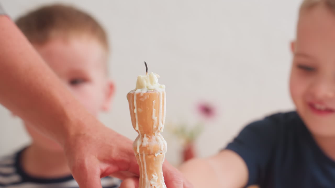 Close up of adult gently removing child hand from candle stand after extinguishing flame while special child sits nearby watching quietly during calm indoor moment showing care
