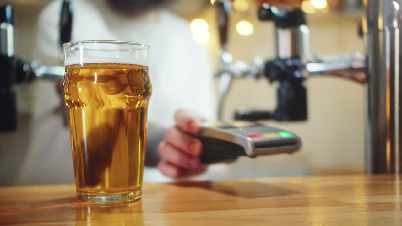 Un cliente paga la birra con una carta di credito contactless in un bar
