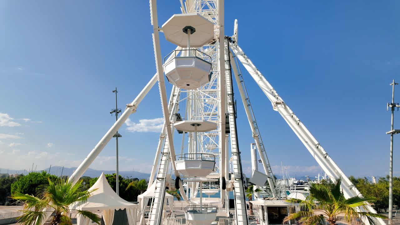 Side view of white ferris wheel rotating in Antibes, France