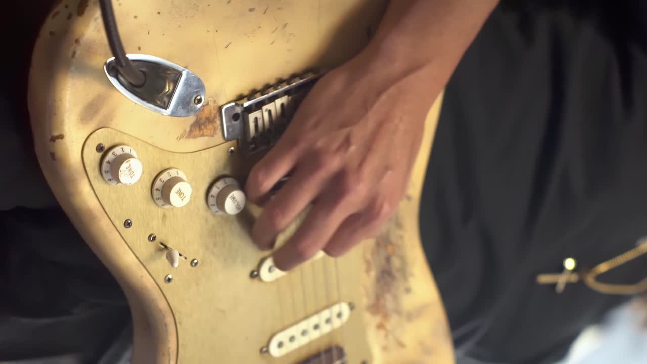 hombre tocando una guitarra eléctrica gastada