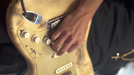 man playing a worn out electric guitar