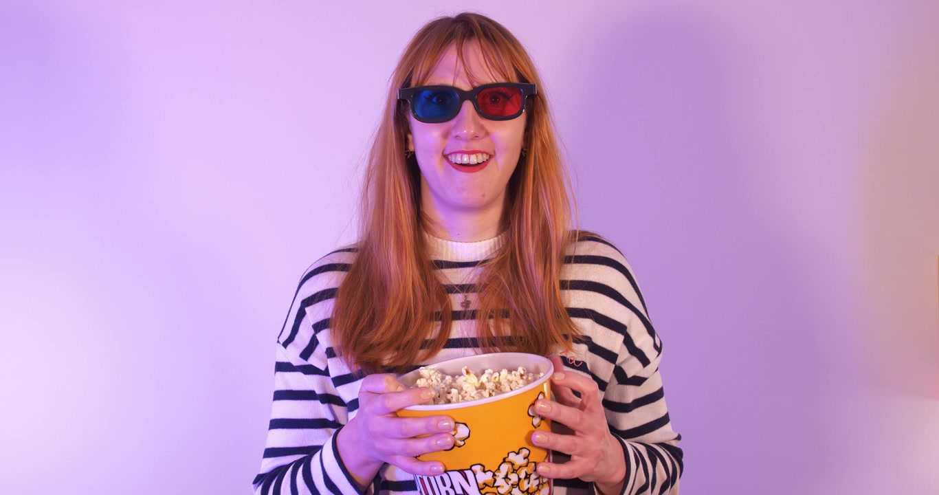 Girl watching a movie with 3d glasses and eating popcorn