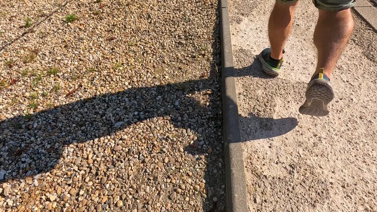 Persona che cammina lungo un sentiero di pietra illuminato dal sole