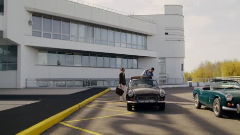 couple leaving vintage cars in front of modern building