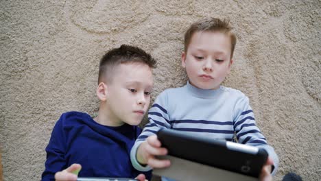 boys using mobile gadgets at home. close up view of two brothers playing on gadgets while lying on floor