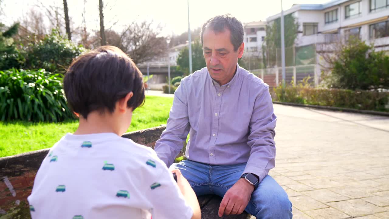 Father and son playing on a bench in a park