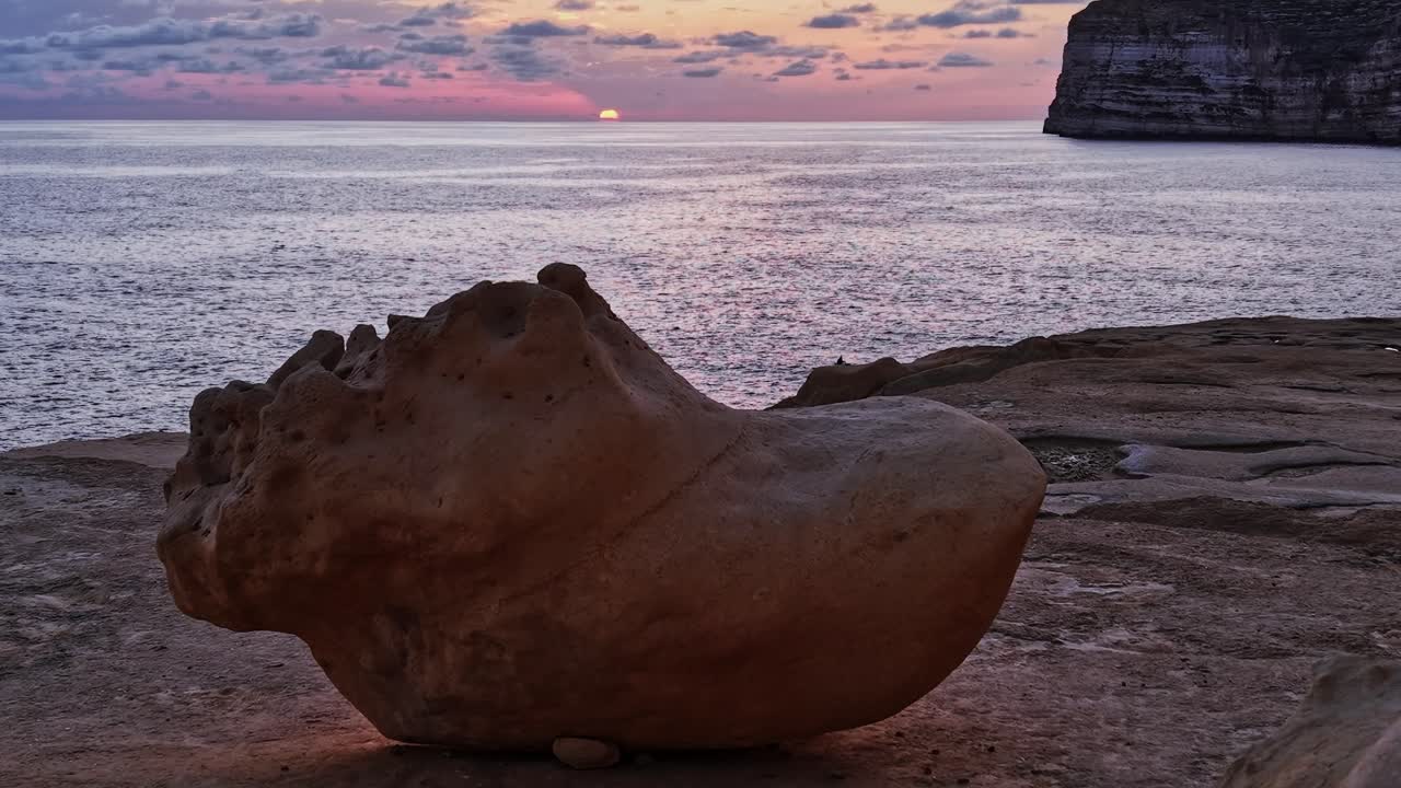 Tramonto sul mare vicino alle rocce a Malta, con scogliere in lontananza