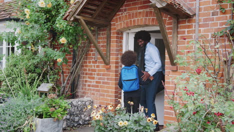 Un-Hombre-Negro-De-Mediana-Edad-Elegantemente-Vestido-Y-Su-Hijo-Preadolescente-Con-Uniforme-Escolar-Saliendo-De-Su-Casa-Por-La-Mañana,-Vista-Exterior,-Longitud-Completa