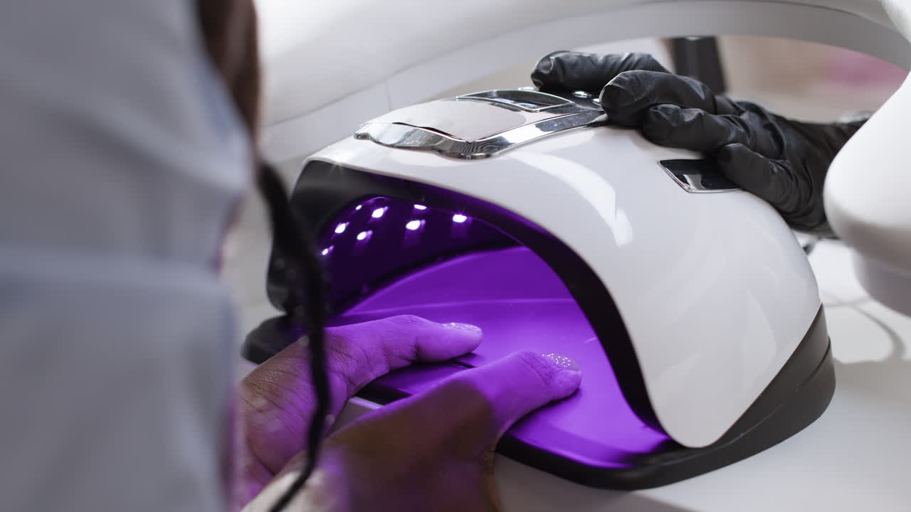 Onicotecnica che applica smalto gel con lampada UV.