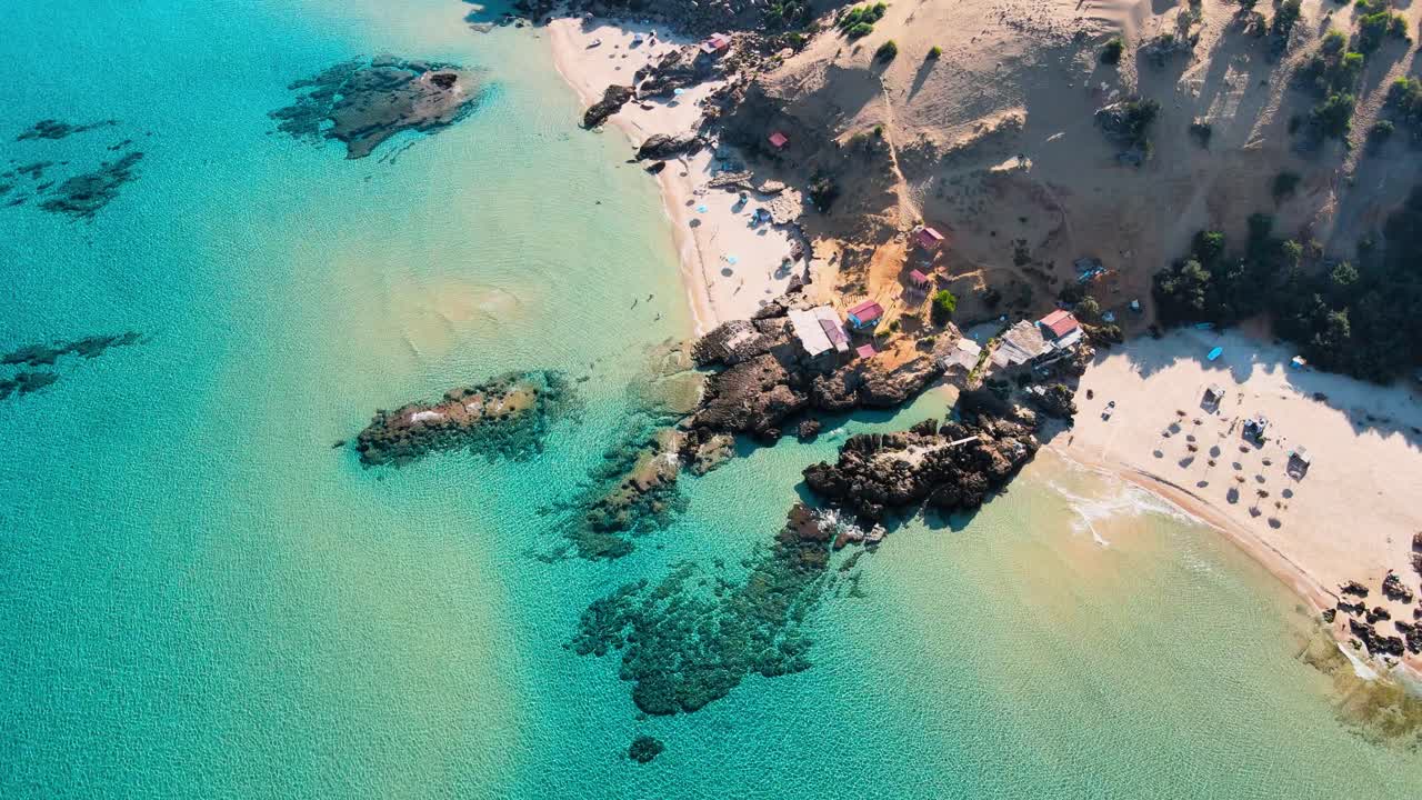 Stunning aerial view of a secluded beach in Tunisia, crystal-clear turquoise waters, and charming beach huts.