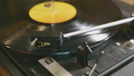 slow camera move across a spinning vinyl lp record as a hand puts the needle onto the grooves of the record