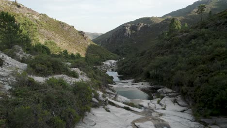 Forward-aerial-view-of-stream-bed-with-large-stones-and-small-pools-of-water