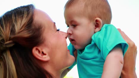 madre feliz frotando las narices con un bebé lindo hijo en el parque