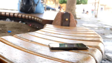 un teléfono celular negro tendido en un banco de madera