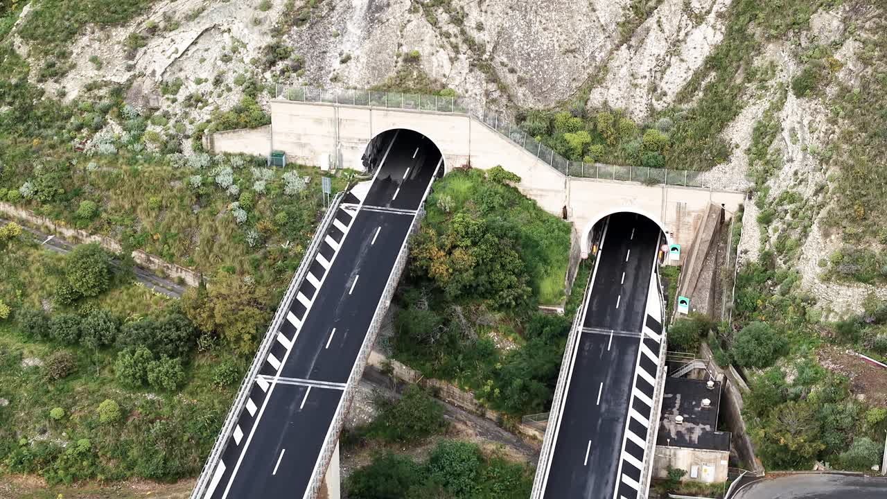 High angle aerial static of cars entering and exiting tunnels of Taormina elevated highway, Italy