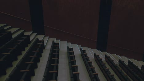 top-down-view-of-multiple-rows-of-empty-seats-in-a-dimly-lit-theater-hall,-creating-a-patterned-perspective