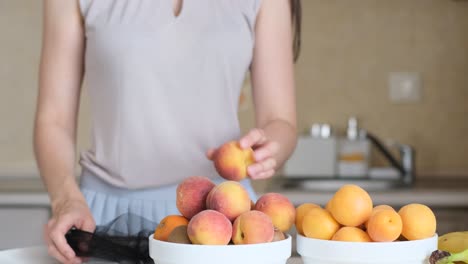 woman puts ripe fruit in a plate in the kitchen woman puts ripe fruit in a plate in the kitchen vegetarianism healthy eating ecobags ecology