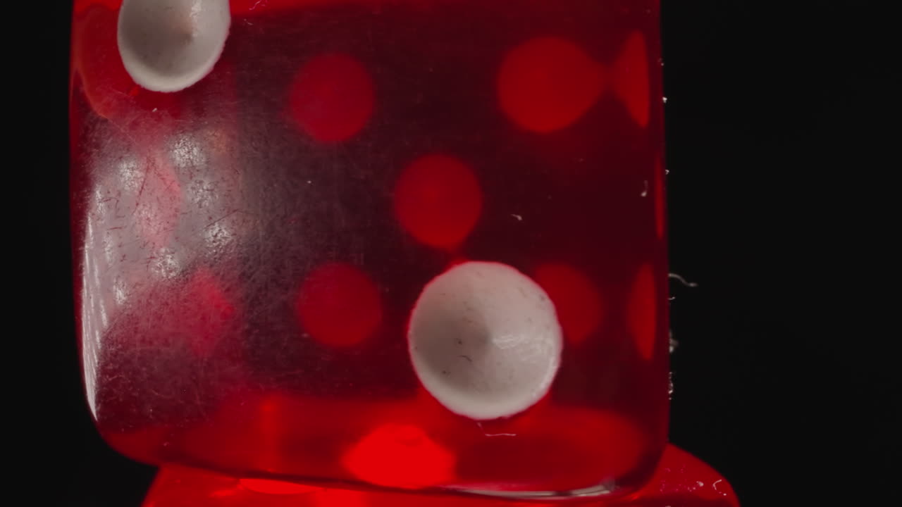 밝은 빛을 반사하는  ⁇  점들이 있는 투명한 빨간색 주사위