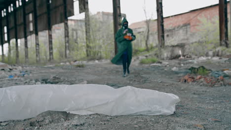 human in protective suit in radioactive place. man in safety costume and gas mask with flowers walking in abandoned place. chemical attack. pollution of the environment.
