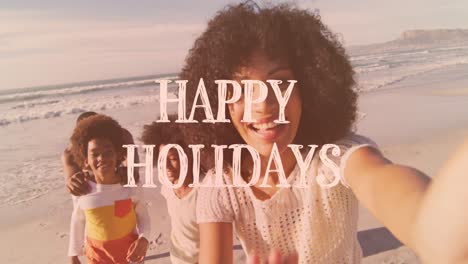 animation of happy holidays text over african american family on the beach