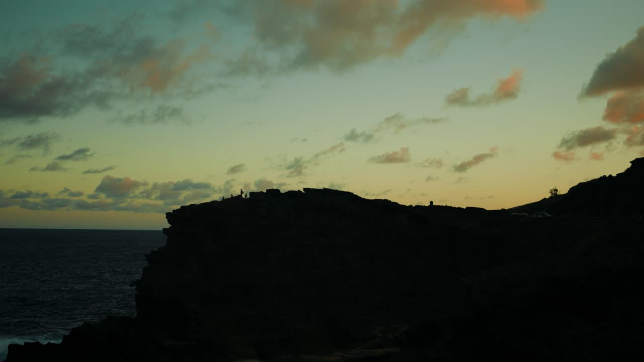 Persone in silhouette sulle rocce al tramonto alle Hawaii
