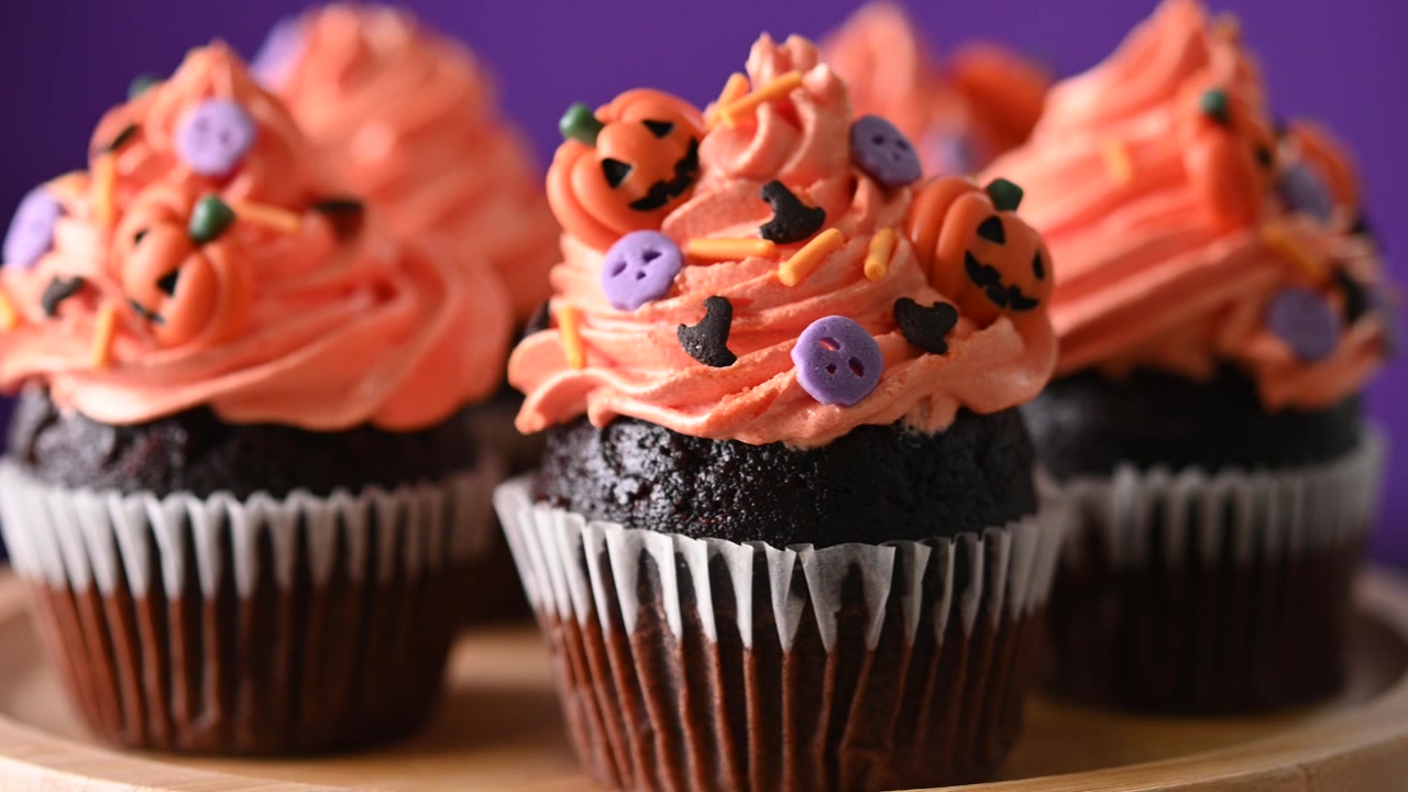 Deliziosi cupcake al cioccolato di Halloween con glassa all'arancia e decorazioni a forma di zucca.