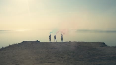 the people with a color bombs standing on the edge of seashore