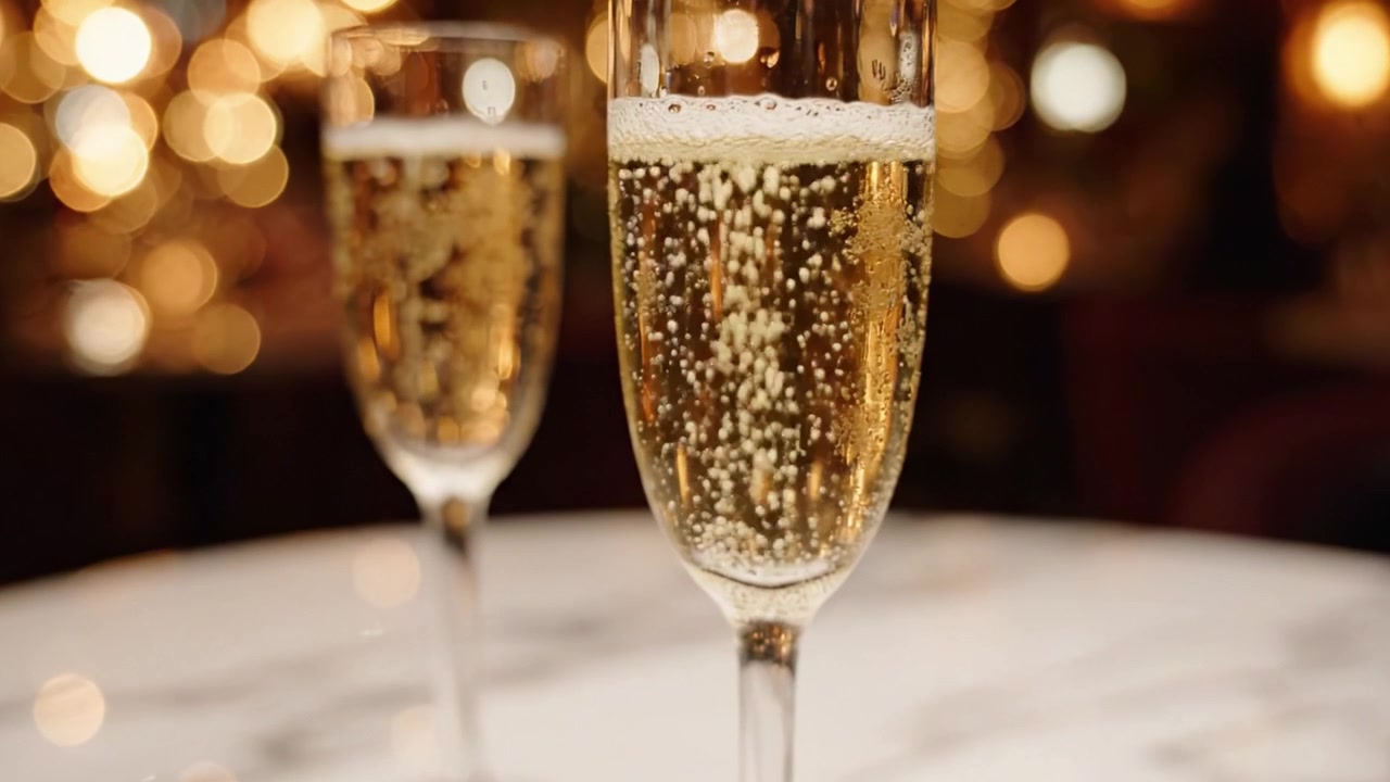 Celebrazione con bollicine: un primo piano di due eleganti flûte piene di champagne frizzante, perfettamente immortalate su uno sfondo scintillante di luci calde.