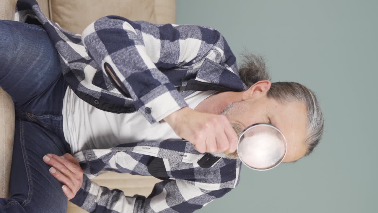 video vertical de un anciano mirando a la cámara con lupa.