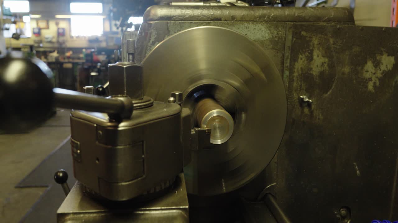 Close-up of a conventional lathe machine performing a facing operation on a metal workpiece inside a workshop. Industrial scene with precision machining and traditional metalworking