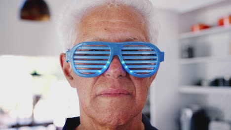hombre mayor en casa usando novedad parpadeando gafas de fiesta