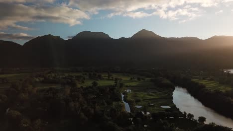 Wide drone shot of Hanalei valley at sunset with mountains and river in Hawaii