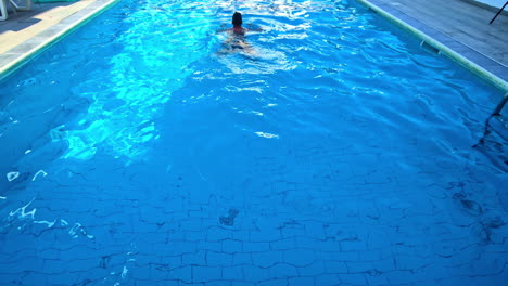 man swimming in breaststroke technique in swimming pool. rear shot, slow motion