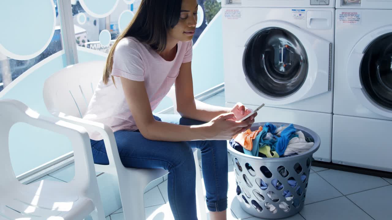 mujer usando teléfono móvil en la lavandería 4k