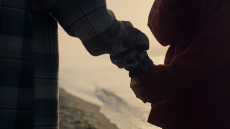 Couple-walking-on-ocean-beach-at-sunset.-Closeup-woman-and-man-holding-hands