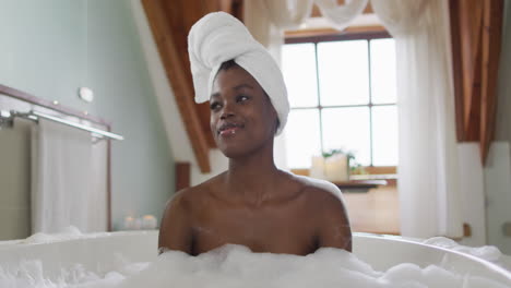 happy african american attractive woman relaxing in foam bath in bathroom