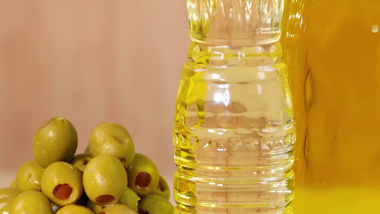 Close-up of olive oil bottles, green olives, and assorted seeds on a colorful background.