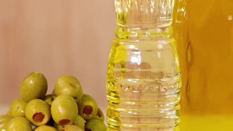 close-up of olive oil bottles, green olives, and assorted seeds on a colorful background.