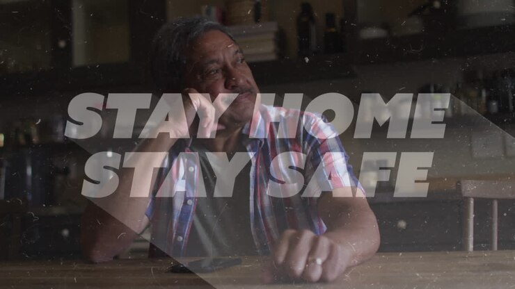 Animation of stay home stay safe text over worried senior man at home