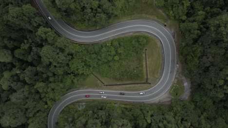 aerial time lapse: traffic drives around loop, tropical forest highway