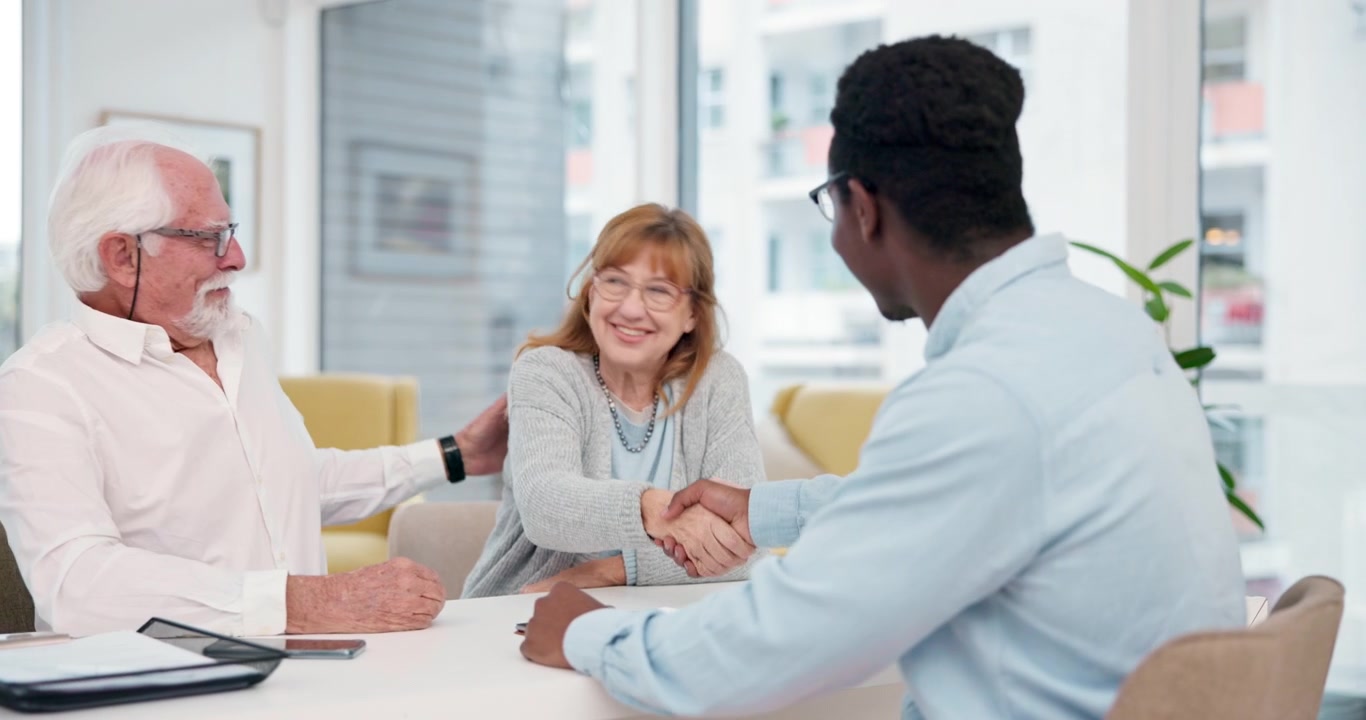 Senior Couple Shaking Hands with Financial Advisor in Office