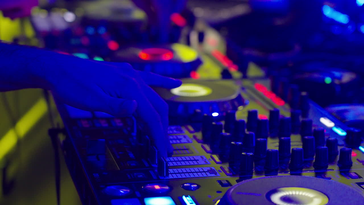 DJ's Hands Mixing Music on a Controller in a Nightclub