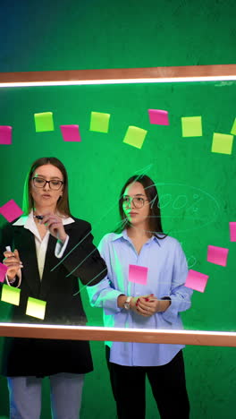 business partners stand at the glass board discussing numbers written on it. communication at work, brainstorming and planning. vertical video.