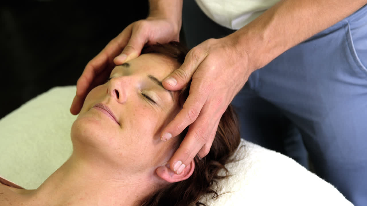Fisioterapeuta dando masaje en la cabeza a una paciente