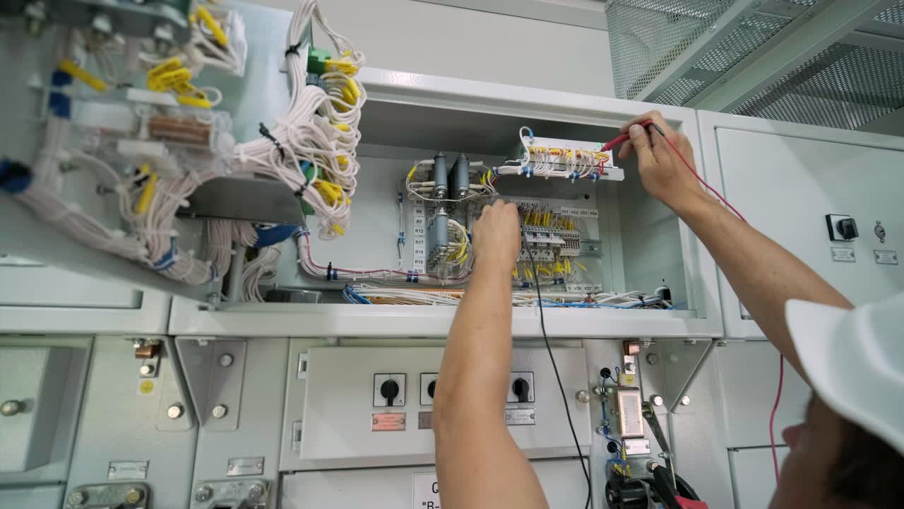 el ingeniero eléctrico que trabaja comprueba la tensión de corriente eléctrica y la sobrecarga en la parte delantera del gabinete del centro de carga o de la unidad de consumo para el mantenimiento en la sala principal del sistema de distribución de energía.