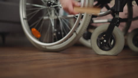 Woman-sits-in-wheelchair-reaching-hand-to-take-book-on-floor