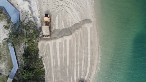 drone view looking down on heavy machinery moving sand on a coastal erosion project