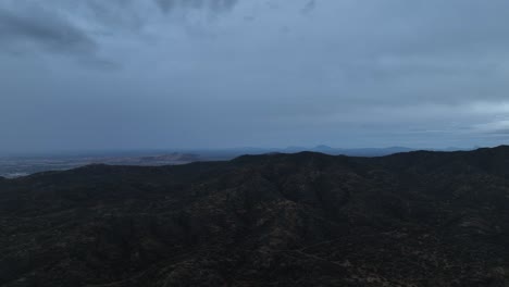 aerial-shot-of-drone-flying-over-a-mountain-in-cloudy-day
