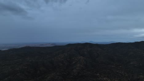 aerial shot of drone flying over a mountain in cloudy day