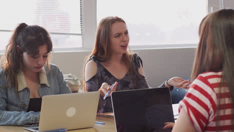 Grupo-De-Estudiantes-Universitarias-Sentadas-En-Un-Escritorio-Usando-Computadoras-Portátiles-Colaborando-Juntas-En-Un-Proyecto